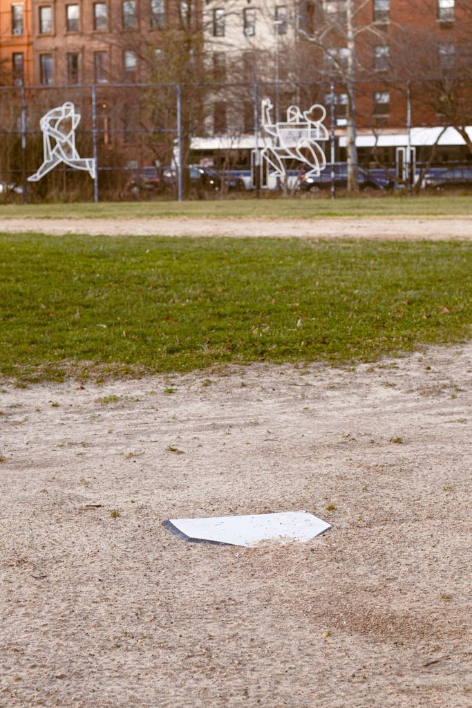 Home plate on an urban baseball field, with city buildings in the background.